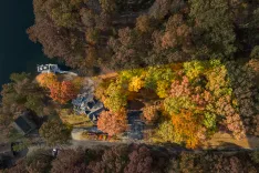 Aerial view of a lakeside neighborhood in autumn with trees displaying vibrant fall foliage.
