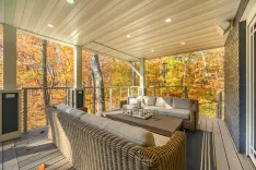 Spacious covered deck with comfortable seating overlooking an autumnal forest.