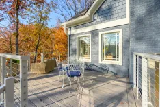 Spacious deck with outdoor seating area overlooking autumn trees at a modern house with gray exterior.