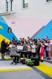 Group of people gathered for an event with a colorful geometric mural in the background.