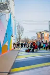 People enjoying an outdoor event with a musician playing the keyboard on a vibrant painted street.