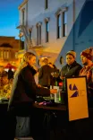 People interacting at an event booth with the Columbus Area Arts Council sign visible during twilight.