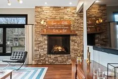 Contemporary living room with a lit fireplace, brick wall, wooden floor, and modern furniture.