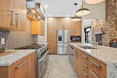 Modern kitchen interior with granite countertops, stainless steel appliances, and wooden cabinets.