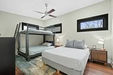Contemporary bedroom with a queen-sized bed and a bunk bed, ceiling fan, and modern decor.