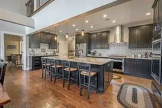 Spacious modern kitchen with a large island, bar stools, stainless steel appliances, and hardwood floors.