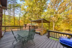 Wooden deck with outdoor furniture surrounded by autumn trees.