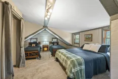 Cozy attic bedroom with twin beds, skylight, wooden ceiling beams, and neutral decor.