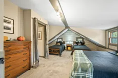 Cozy attic bedroom with twin beds, wooden furniture, and slanted ceilings with a skylight.