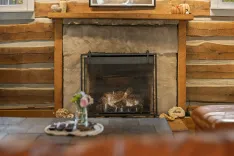 Cozy room with a stone fireplace, wooden mantel, and a decorative figurine on a table in the foreground.