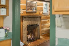 Cozy interior view of a rustic cabin with a stone fireplace, wood paneling, and vintage decor.