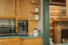 A cozy kitchen corner with wooden cabinets, a microwave, coffee maker, and decorative canisters on the countertop.