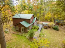 Secluded cabin surrounded by autumn foliage with a connecting wooden deck pathway.