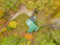 Aerial view of a green-roofed building surrounded by autumn-colored trees.