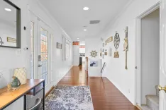 Bright, nautical-themed hallway with wooden flooring, white walls, decorative maritime items, and natural light from doors and windows.