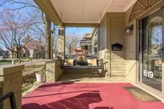 Covered porch area of a house with outdoor seating visible and a red carpet on the floor.