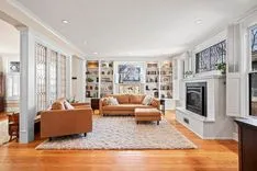Elegant living room interior with hardwood floors, leather sofas, fireplace, and built-in shelving.