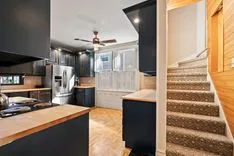 Modern kitchen interior with stainless steel appliances leading to a staircase on the right.