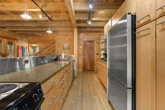 Spacious wooden kitchen interior with stainless steel appliances, granite countertops, and a staircase leading to the upper level.