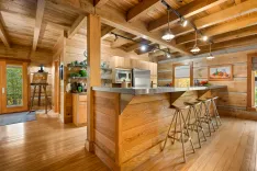 Rustic wooden kitchen interior with a central island, bar stools, and modern appliances under track lighting.