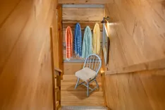 Cozy wooden hallway with colorful towels hanging on the wall and a blue chair with a cushion.