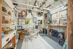 Alt: A well-lit and eclectic garden shed converted into a creative workshop with various tools, artwork, and gardening equipment.