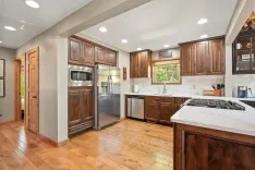 Modern kitchen interior with wooden cabinets, stainless steel appliances, and hardwood floors.