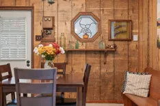 Cozy dining area with rustic wooden walls, antique decor, and a fresh bouquet of flowers on the table.