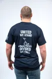 Rear view of a person wearing a dark t-shirt with the text "UNITED WE STAND DIVIDED WE FALL" and a graphic of a group of people planting a flag on a hill.
