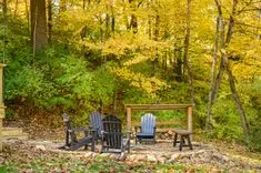 Outdoor wooden furniture set amidst vibrant autumn foliage in a forest clearing.