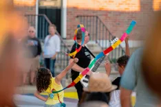 People enjoying an outdoor event with a person juggling colorful clubs in the foreground.