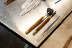 Assorted jewelry making tools including metal files and a hammer on a workbench.