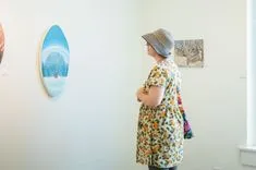 A visitor at an art gallery observing paintings on the wall.