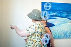 Person in a patterned shirt and hat playing a ring toss game at an event.