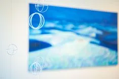 Blurred image of a canvas with abstract blue and white art on a wall, overlayed with transparent circles possibly representing artistic inspiration or creativity.