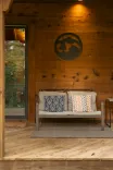 Cozy wooden porch with a couch and decorative pillows, next to an open door, featuring a wall emblem reading "Cabin on the Ridge".