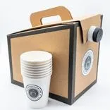Stack of white paper coffee cups with Coffeehouse branding in front of a cardboard drink carrier also with Coffeehouse branding and a built-in handle.