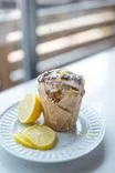 Lemon poppy seed muffin with glaze on a white plate, accompanied by fresh lemon slices.