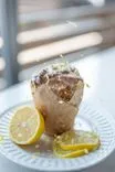Lemon poppy seed muffin with a glazed topping and grated lemon zest, served on a white plate with fresh lemon slices.