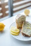 Lemon poppy seed cake slices with icing on a white plate, accompanied by fresh lemon slices.