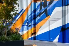 Colorful abstract mural on urban building with a door integrated into the design.