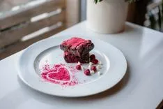 Red velvet brownies on a plate with white chocolate chips and a dusting of raspberry powder forming a heart shape.