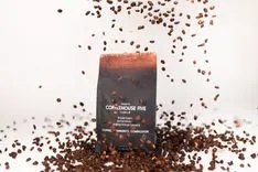 A package of CoffeeHouse Five coffee with coffee beans falling around it on a white background.