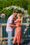Couple kissing under a floral arch on a sunny day.