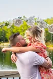 Couple embracing lovingly on a bridge with natural scenery in the background.