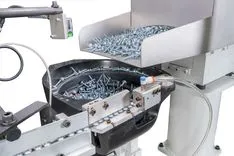 Industrial automated screw feeding and sorting machine in operation, filled with screws.
