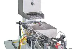 Industrial capsule counting and sorting machine in operation with a hopper full of capsules.