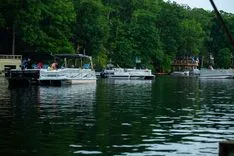 Boats docked at a serene lakeside with dense trees in the background.