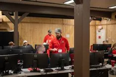 People in red shirts working in a computer lab.
