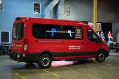 Red van parked indoors with promotional graphics on the side.